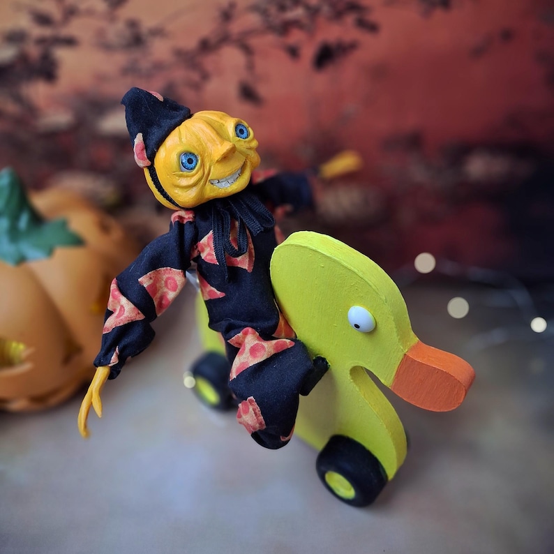 Right angled view of the handmade art doll, playfully pushing a wooden wheeled duck toy with arms outstretched, wearing a whimsical outfit.