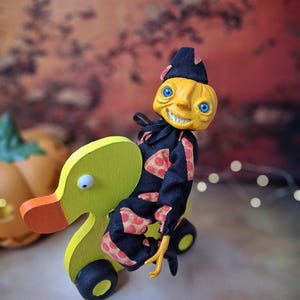 Distant left angled view of the handmade art doll, arms outstretched while playfully pushing a wooden wheeled duck toy, showing her full whimsical outfit and playful pose.