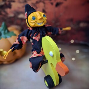 Right side view of the handmade art doll, slightly leaning to the right with arms outstretched while playfully pushing a wooden wheeled duck toy, wearing a whimsical outfit.