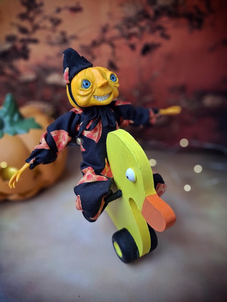 Right side view of the handmade art doll, slightly leaning to the right with arms outstretched while playfully pushing a wooden wheeled duck toy, wearing a whimsical outfit.