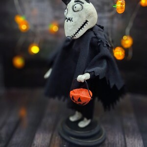 Handmade Sparky Art Doll wearing a black hoodie Halloween-style outfit, holding a pumpkin-shaped trick-or-treat box. Shown from the right profile. Whimsical and spooky Halloween home decor, unique collectible dog doll