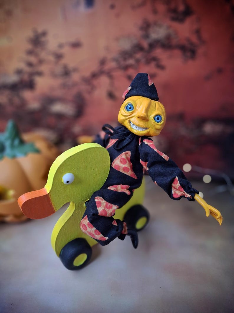 Left angled view of the handmade art doll, playfully pushing a wooden wheeled duck toy with arms outstretched, wearing a whimsical outfit.