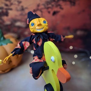 Front view of the handmade art doll, slightly leaning to the right, arms outstretched while playfully pushing a wooden wheeled duck toy, wearing a whimsical outfit.