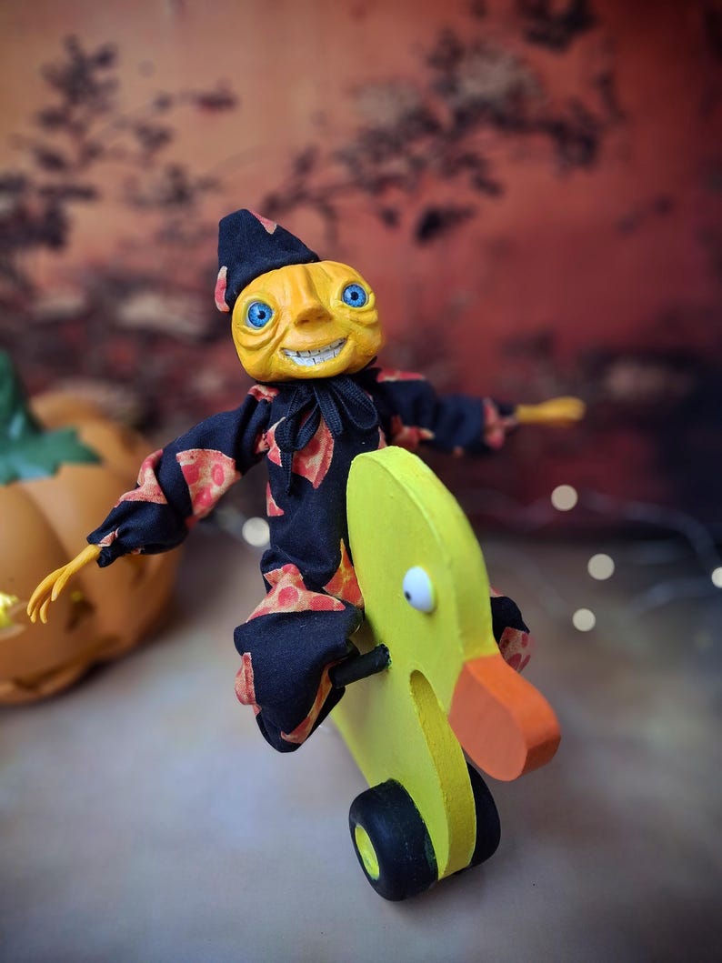 Front view of the handmade art doll, slightly leaning to the right, arms outstretched while playfully pushing a wooden wheeled duck toy, wearing a whimsical outfit.