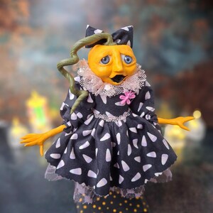Front view of the handmade spooky Halloween pumpkin art doll, slightly leaning to the right, wearing a pumpkin-inspired outfit and showing hand-painted facial details and festive Halloween accents.