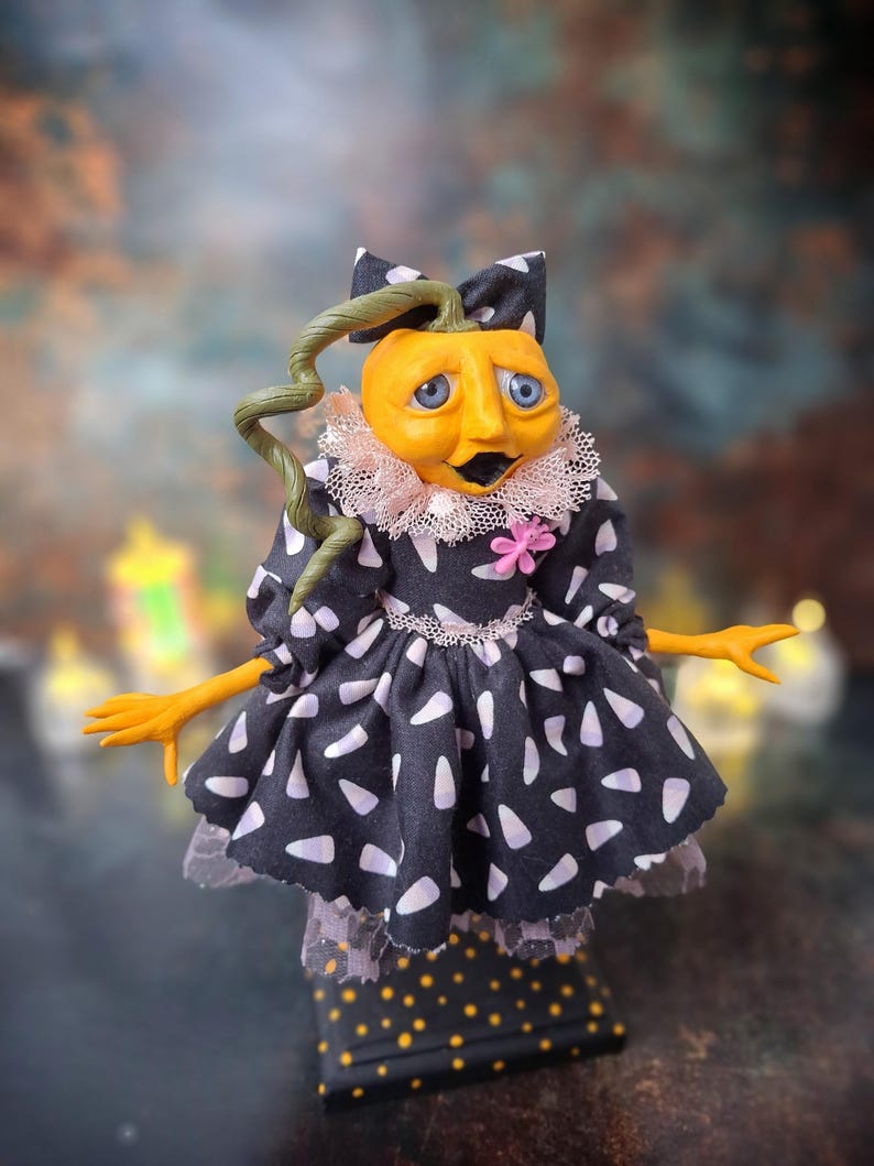 Front view of the handmade spooky Halloween pumpkin art doll, slightly leaning to the right, wearing a pumpkin-inspired outfit and showing hand-painted facial details and festive Halloween accents.
