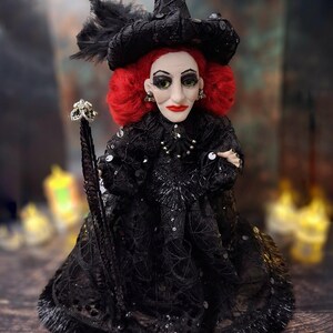 Front view of the handmade fancy witch art doll at medium distance, showing her hand-painted face, whimsical witch outfit, and enchanting accessories.