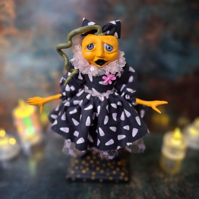 Front view of the handmade spooky Halloween pumpkin art doll, wearing a pumpkin-inspired outfit with hand-painted details, standing upright as a festive fall decor piece.