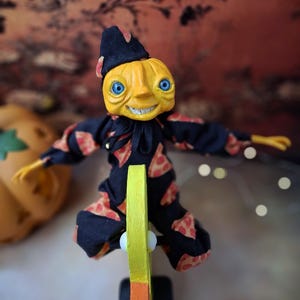 Top-down view of the handmade art doll standing upright, arms outstretched while playfully pushing a wooden wheeled duck toy, looking toward the camera, wearing a whimsical outfit.