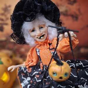 Close-up of the witch art doll from chest to face, showing her detailed hand-painted features, cute Halloween outfit, and whimsical spooky expression.