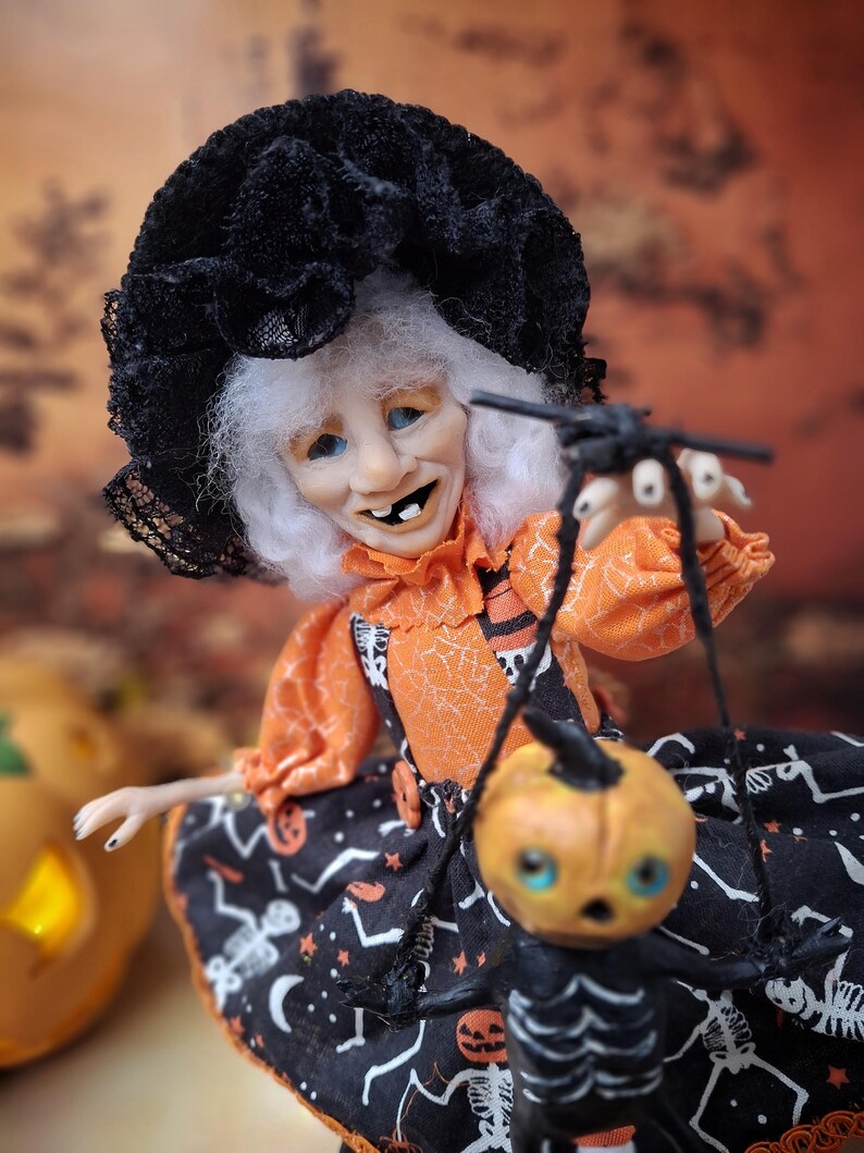 Close-up of the witch art doll from chest to face, showing her detailed hand-painted features, cute Halloween outfit, and whimsical spooky expression.