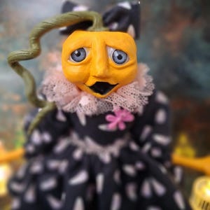 Close-up front view of the handmade spooky Halloween pumpkin art doll, focusing on her detailed hand-painted face and pumpkin-inspired outfit.