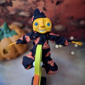 Overhead view of the handmade art doll from above, playfully pushing a wooden wheeled duck toy with arms outstretched, looking toward the camera, dressed in a whimsical outfit.