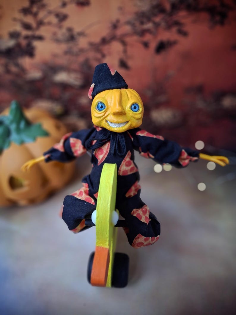 Overhead view of the handmade art doll from above, playfully pushing a wooden wheeled duck toy with arms outstretched, looking toward the camera, dressed in a whimsical outfit.
