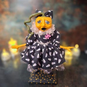 Front wide-angle view of the handmade spooky Halloween pumpkin art doll, showing her full pumpkin-inspired outfit, hand-painted face, and festive Halloween details.