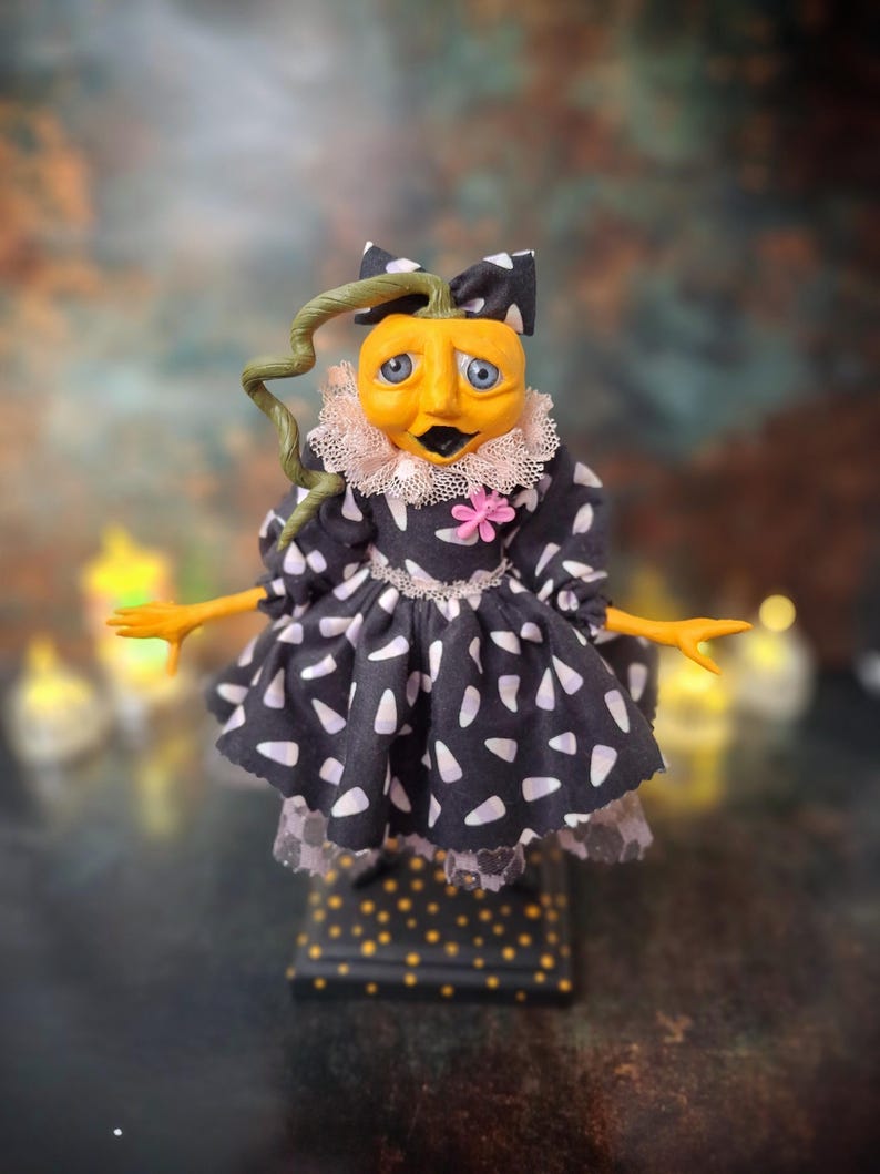 Front wide-angle view of the handmade spooky Halloween pumpkin art doll, showing her full pumpkin-inspired outfit, hand-painted face, and festive Halloween details.
