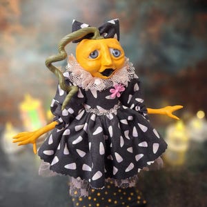 Front view of the handmade spooky Halloween pumpkin art doll, angled slightly to the right, featuring a pumpkin-inspired outfit, detailed hand-painted face, and seasonal Halloween-themed details.