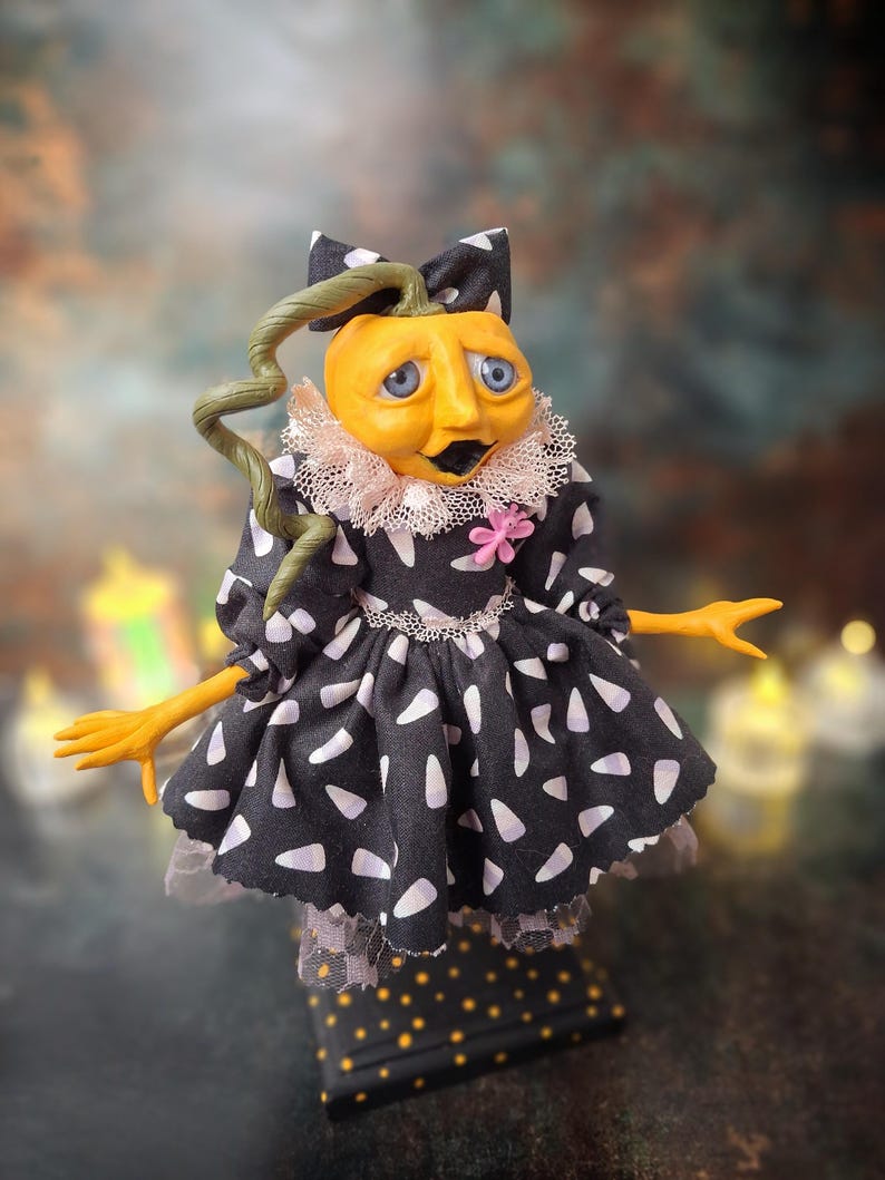 Front view of the handmade spooky Halloween pumpkin art doll, angled slightly to the right, featuring a pumpkin-inspired outfit, detailed hand-painted face, and seasonal Halloween-themed details.