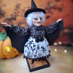 Right side view of the handmade witch art doll, showing her witch-themed Halloween outfit, hand-painted facial details, and bat wings fully extended in a spooky seasonal display.