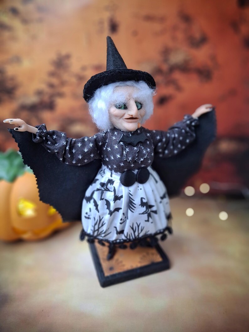 Right side view of the handmade witch art doll, showing her witch-themed Halloween outfit, hand-painted facial details, and bat wings fully extended in a spooky seasonal display.