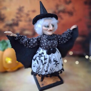 Wide-angle right side view of the handmade witch art doll, highlighting her full witch-themed Halloween outfit, detailed hand-painted face, and fully extended bat wings.