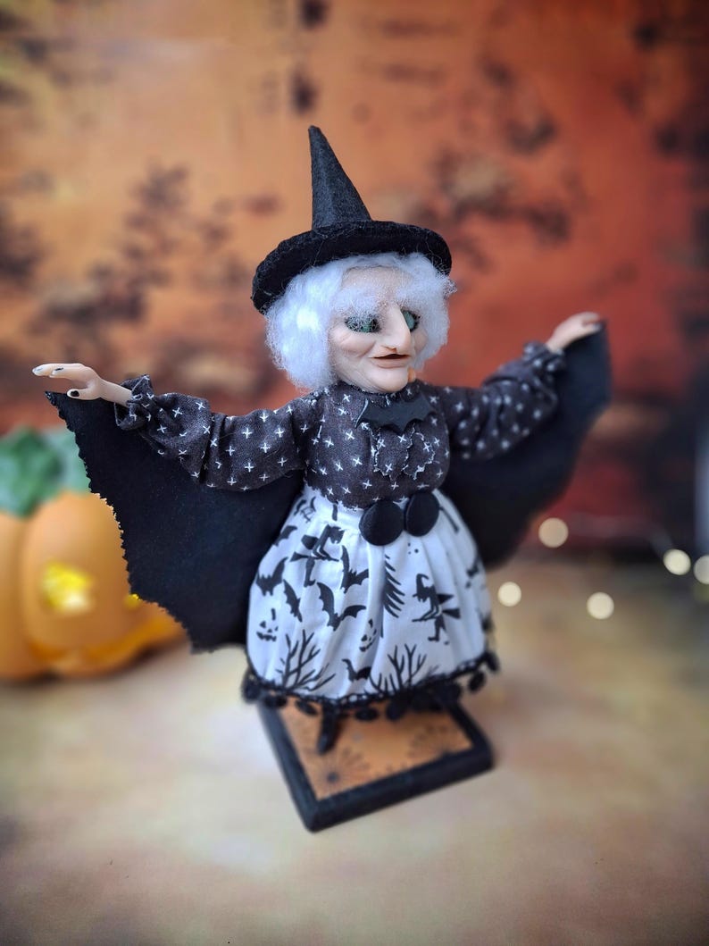 Wide-angle right side view of the handmade witch art doll, highlighting her full witch-themed Halloween outfit, detailed hand-painted face, and fully extended bat wings.