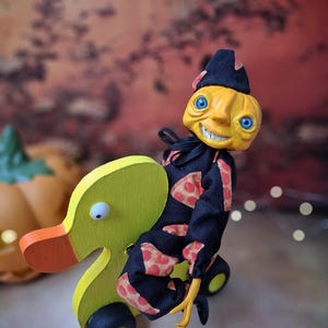 Close-up left angled view of the handmade art doll, showing her arms outstretched while playfully pushing a wooden wheeled duck toy, with detailed hand-painted features and whimsical outfit.