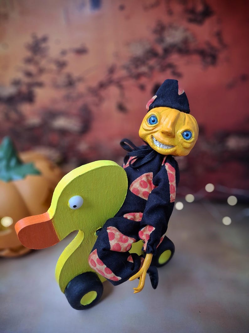 Close-up left angled view of the handmade art doll, showing her arms outstretched while playfully pushing a wooden wheeled duck toy, with detailed hand-painted features and whimsical outfit.