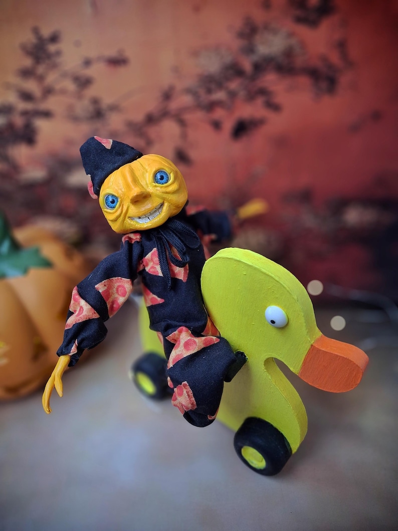 Side view from the right of the handmade art doll, arms outstretched while playfully pushing a wooden wheeled duck toy, showing her whimsical outfit and hand-painted details.