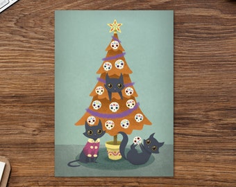 Könnte beinhalten: Ein Weihnachtsbaum, der mit Zucker Schädel Ornamenten und drei schwarzen Katzen geschmückt ist. Die Katzen tragen lila und orangefarbene Pullover und eine hält ein Zucker Schädel Ornament.
