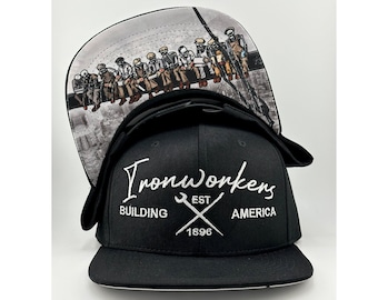 May include: Black and white baseball cap with a white embroidered logo that says "Ironworkers Building America Est. 1896". The back of the cap features a graphic of a group of men sitting on a beam.