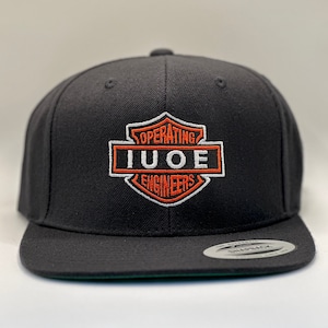 May include: A black and orange embroidered baseball cap with the text "OPERATING IUOE ENGINEERS" in a shield shape.