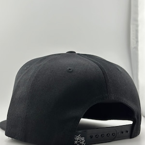 May include: Black baseball cap with an adjustable strap and a small white logo on the back.
