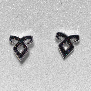Könnte beinhalten: Ein Paar silberne Ohrstecker mit einem schwarzen Glitzer-Runen-Symbol. Die Rune ist ein stilisiertes Symbol mit einer Diamantenform in der Mitte.