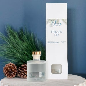 May include: A frosted glass reed diffuser bottle with a gold cap and a white box. The box and bottle both read "Fraser Fir". The bottle is next to pine needles and pine cones. The net weight is 340 grams.