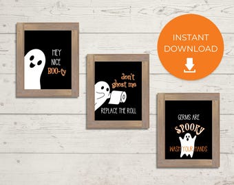 Può includere: Tre stampe incorniciate a tema Halloween con sfondi neri e illustrazioni di fantasmi bianchi. Le stampe presentano frasi umoristiche come "Hey Nice Boo-ty", "Don't Ghost Me, Replace the Roll" e "Germs Are Spooky, Wash Your Hands."