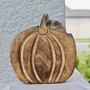 Puede incluir: Decoración de madera con forma de calabaza y diseño tallado. La calabaza es de color marrón oscuro con vetas de madera visibles y un tallo. Ideal para decoración de otoño.
