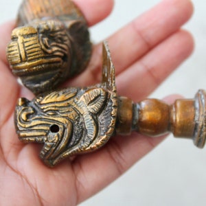 Puede incluir: Dos pomos de puerta antiguos de latón con diseños detallados de cabeza de animal. Los pomos son ornamentados y tienen un aspecto vintage.