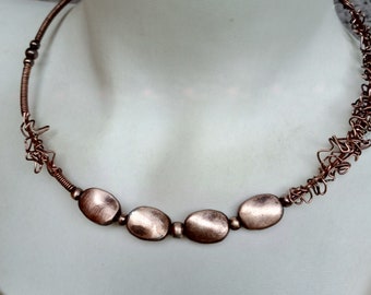 May include: A copper necklace with a delicate wire design and four oval-shaped copper beads.