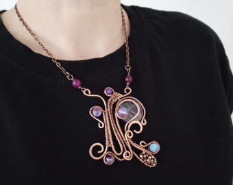 May include: A copper wire necklace with a large amethyst pendant and smaller amethyst and opal stones. The necklace is on a chain with small purple beads.