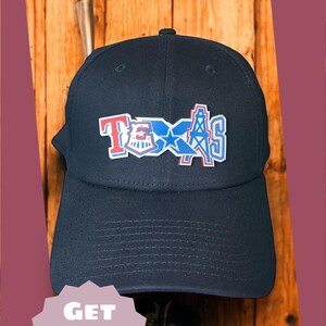May include: Navy blue baseball cap with a colorful Texas design. The design includes the word "Texas" in red, white, and blue, with a star and oil derrick graphic. The text "TEXAS!" is above the cap.
