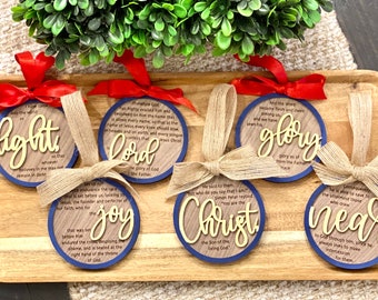 May include: Six wooden Christmas ornaments with blue trim and gold lettering. Each ornament features a different word and a Bible verse. The words are "light", "Lord", "joy", "Christ", "glory", and "near".