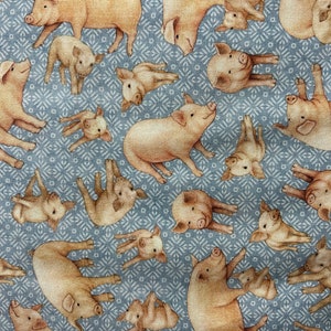 Könnte beinhalten: Ein blauer Stoff mit einem sich wiederholenden Muster aus rosa Schweinen. Die Schweine sind in verschiedenen Posen, einige liegen, einige stehen und einige sind zusammengerollt. Der Stoff ist perfekt zum Quilten, Nähen oder Basteln.