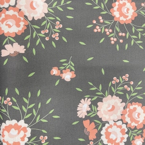 May include: Dark gray fabric with a repeating floral pattern. The design features clusters of peach and white flowers, small pink blossoms, green leaves, and tiny pink berries. The overall aesthetic is a vintage, botanical theme.