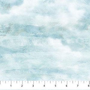 May include: A light blue and white fabric featuring a marbled, cloud-like pattern with soft, blended textures. A white ruler is visible at the bottom edge, showing measurements in inches from 1 to 8, indicating the scale of the textile design.