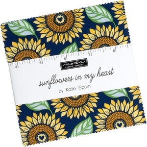 May include: A fabric square with a sunflower pattern in shades of yellow, green, and blue. The fabric has the text "sunflowers in my heart" and "by Kate Spain" printed on it.