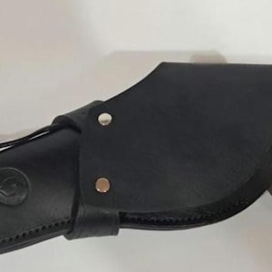 May include: A black leather holster featuring a curved flap secured with two silver-toned metal rivets. The holster has a circular embossed logo on the side and a brown wooden handle of a firearm is visible protruding from the open end of the casing.