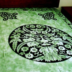 May include: Green tapestry with a black and white design of a green man's face surrounded by leaves and flowers. The design is in a circle in the center of the tapestry. There are two smaller black and white designs in the corners of the tapestry.