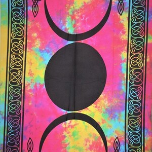 May include: A tapestry with a tie-dye background in shades of pink, yellow, blue, and green. The center of the tapestry features a black triple moon symbol with a circle in the middle. The tapestry is bordered with a black Celtic knot design.
