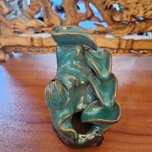 May include: A teal blue ceramic incense burner shaped like a mountain with a small hole at the top. The burner has a textured surface and is designed to hold incense cones.